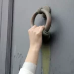 close de uma pessoa batendo na porta com uma velha aldrava 700x467 1